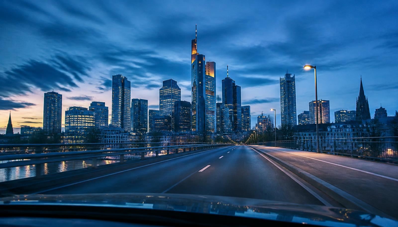 Frankfurter Skyline in der Abenddämmerung aus der Fahrerperspektive über eine Mainbrücke